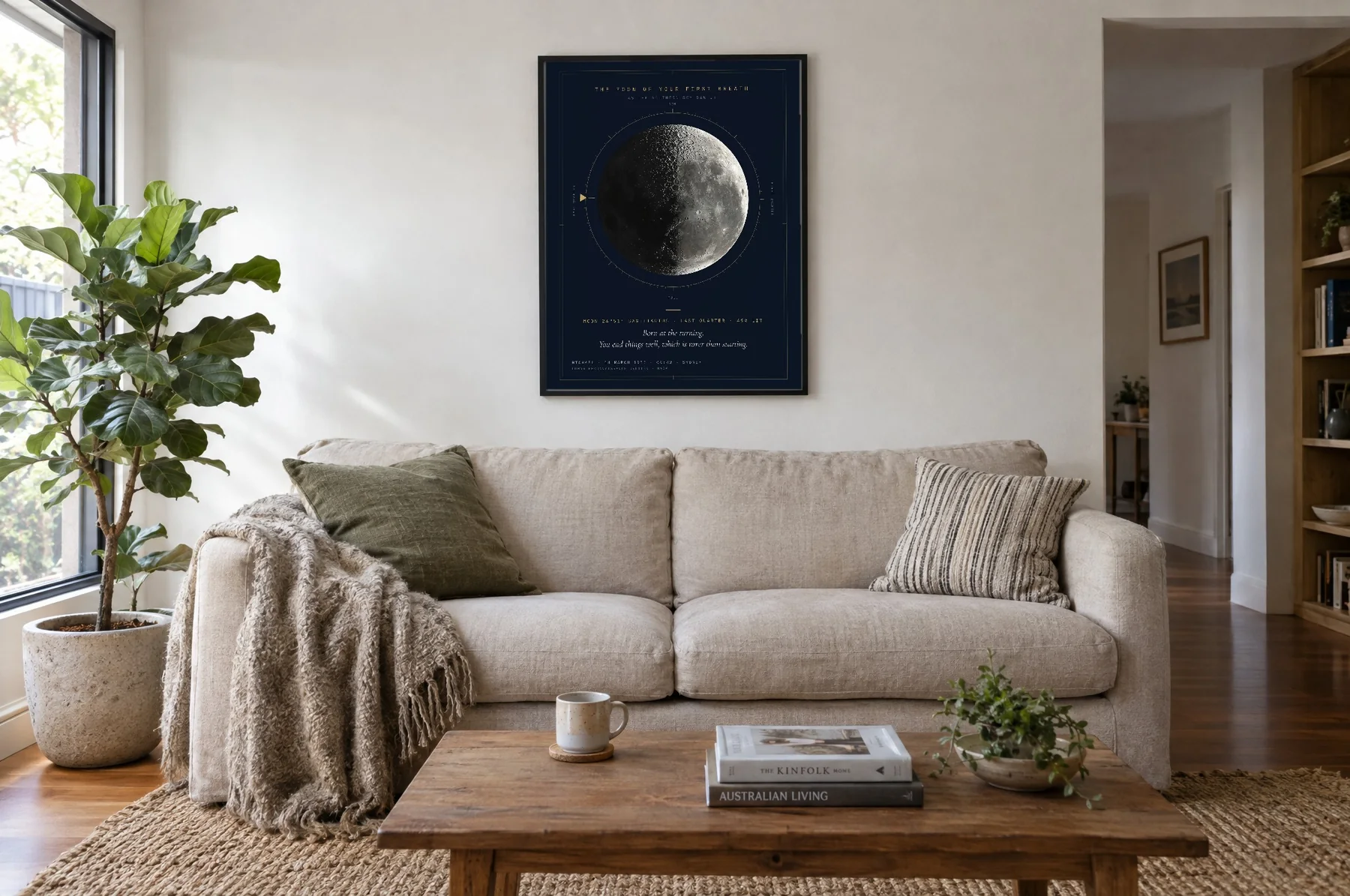 The Moon print on navy paper in a black frame, hanging above a linen sofa in a sunny living room